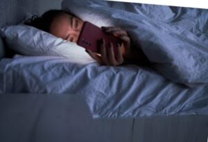 Lady messaging on smartphone in bed